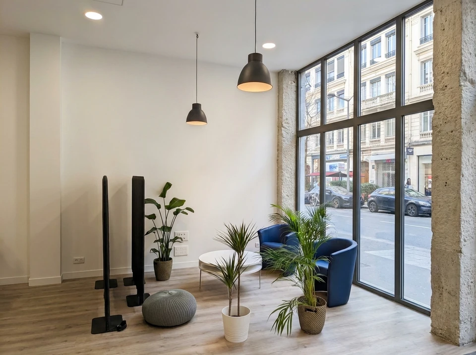 Espace de réception moderne avec coin salon : deux fauteuils barrel chair en velours bleu marine, table basse ronde blanche, plantes tropicales (strelitzia, dracaena, areca)