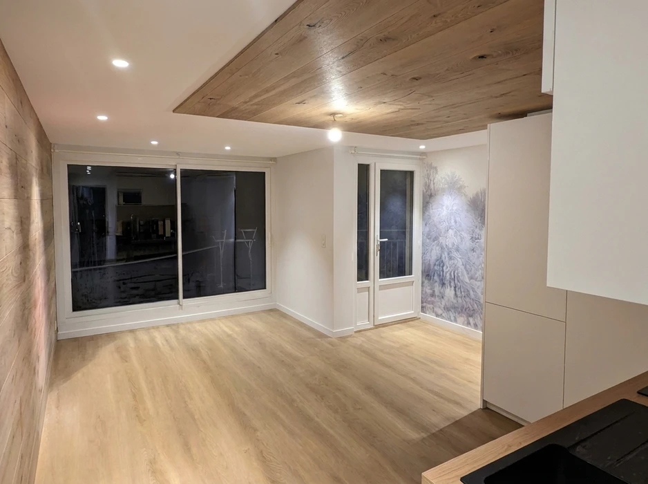 Pièce rénovée vide, sol en parquet stratifié chêne clair, plafond mixte blanc et lambris bois massif vieilli avec spots encastrés LED