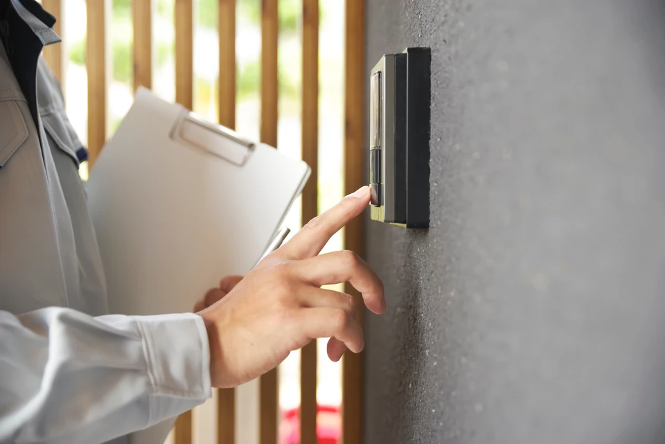 Homme en veste noire pointant du doigt un écran tactile mural affichant un plan d'étage 2D d'une maison