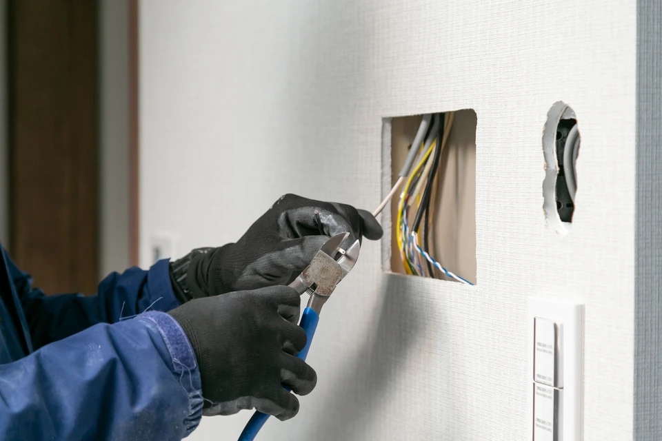 Homme en veste noire pointant du doigt un écran tactile mural affichant un plan d'étage 2D d'une maison